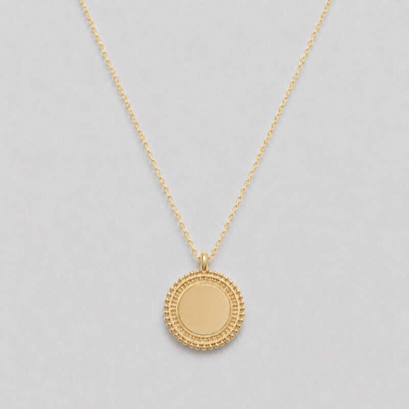 Collier en plaqué or 3 microns 18 carats pour femme qui se compose d'une chaîne classique et d'un pendentif rond au pourtour travaillé, style ethnique. L'intérieur du médaillon est lisse et peut être personnalisé avec une gravure.