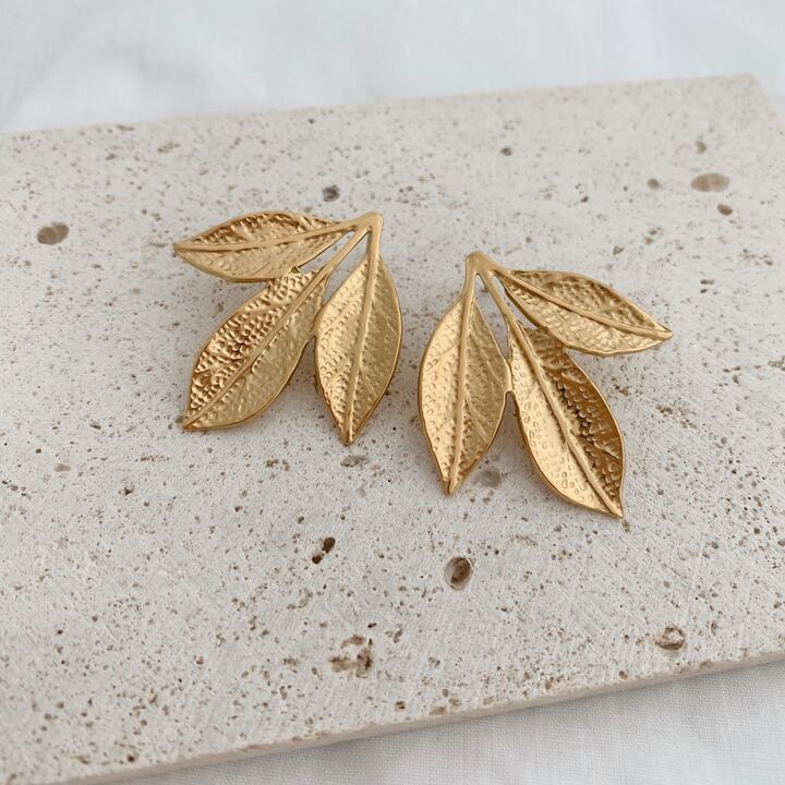 Boucles d'oreilles imposantes pour femme en acier inoxydable doré qui se compose de trois jolies feuilles. La paire de boucles d'oreille est légère à porter.