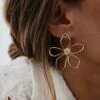 Grandes boucles d'oreilles en acier inoxydable doré au motif floral ajouré. La fleur a un léger fini irrégulier et martelé au niveau des pétales. Dimensions d'une boucle d'oreille : 5 x 4,2 cm. Le bijou se ferme à l'aide d'un fermoir papillon ou d'un poussoir en silicone. La paire de boucles d'oreilles est très légère à porter malgré sa taille imposante. Par mesure d’hygiène, les boucles d’oreilles ne sont ni reprises, ni échangées Cette paire est garantie sans nickel, sans cadmium, sans sel de plomb. Elle résiste à l’eau et ne noircit pas.