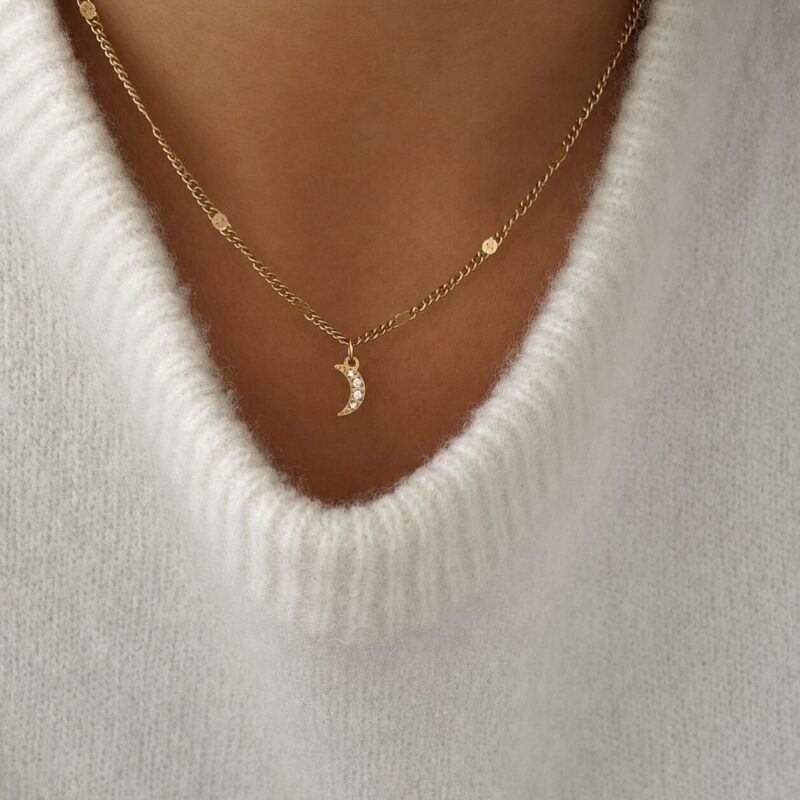 Collier pour femme fin et tendance composé d'une fine chaîne en acier doré et d'un pendentif en forme de croissant de lune.