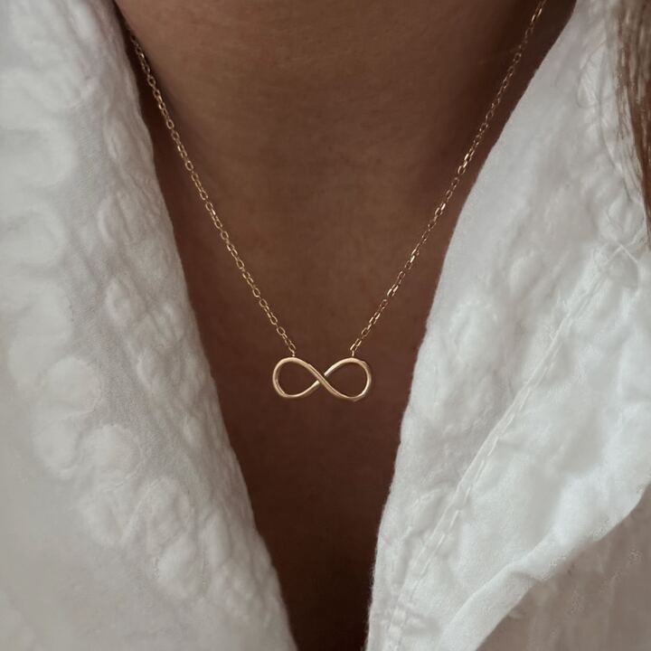 Collier en plaqué or 3 microns 18 carats pour femme Ce bijou est composé d'une chaîne classique ornée d'un empiècement au symbole "infini" Dimensions pendentif : 1.7 cm x 0.7 cm Ajustable à 40.5 cm, 42.5 cm et 45.5 cm Fermoir mousqueton