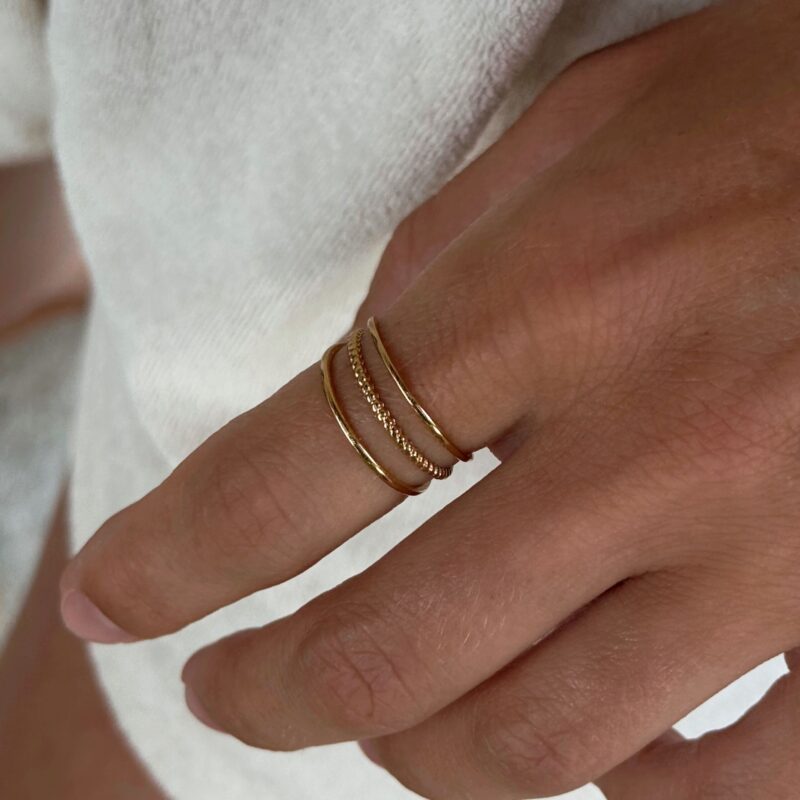 Bague dorée pour femme ajourée en acier inoxydable qui se compose de trois anneaux fins. La taille du bijou est ajustable.