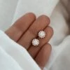Boucles d'oreilles pour femme en plaqué or 3 microns 18 carats et oxydes de zirconium. Ce bijou, style puces d'oreille, se compose de petits diamants de synthèse scintillants en forme de fleur. La boucle mesure 0,9 centimètres de diamètre.
