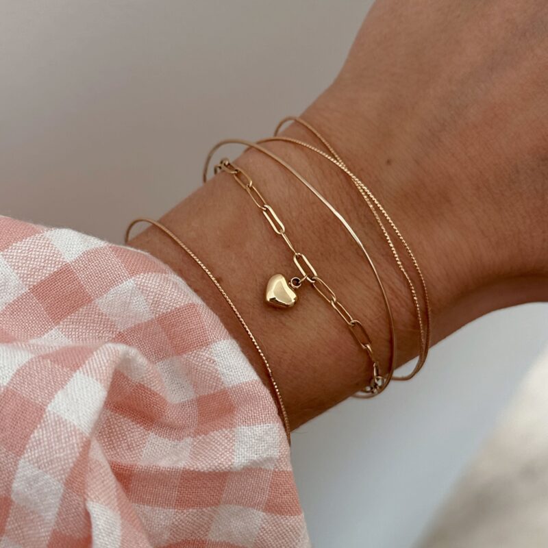 Bracelet fin à prix doux décoré d'un petit coeur bombé à offrir à une personne chère à votre coeur. Le bracelet est en acier inoxydable doré et se compose d'une maille décorée de maillons fins et ovales.