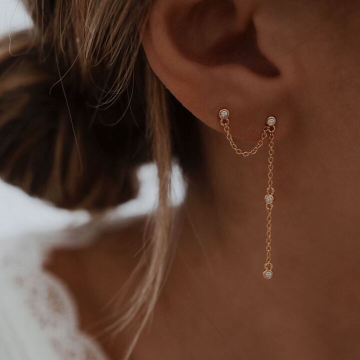 Mono boucle d'oreille pendante en plaqué or 3 microns 18 carats, vendue à l'unité Ce bijou se compose de deux puces décorée d'un oxyde de zirconium et d'une chaînette ornée également de petits oxydes de zirconium Cette pièce nécessite d'avoir deux trous à votre lobe d'oreille Longueur totale boucle avec chaînette : 4.3 cm Longueur de la chaîne qui relie les deux boucles : environ 2 cm Fermoir papillon. Par mesure d’hygiène, les boucles d’oreilles ne sont ni reprises, ni échangées Tendance, mode, shop, shopping accessoire femme