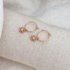 Boucles d'oreilles type créoles en plaqué or 3 microns 18 carats qui se composent d'un pendentif en forme de fleur, sertie au centre d'un oxyde de zirconium.
