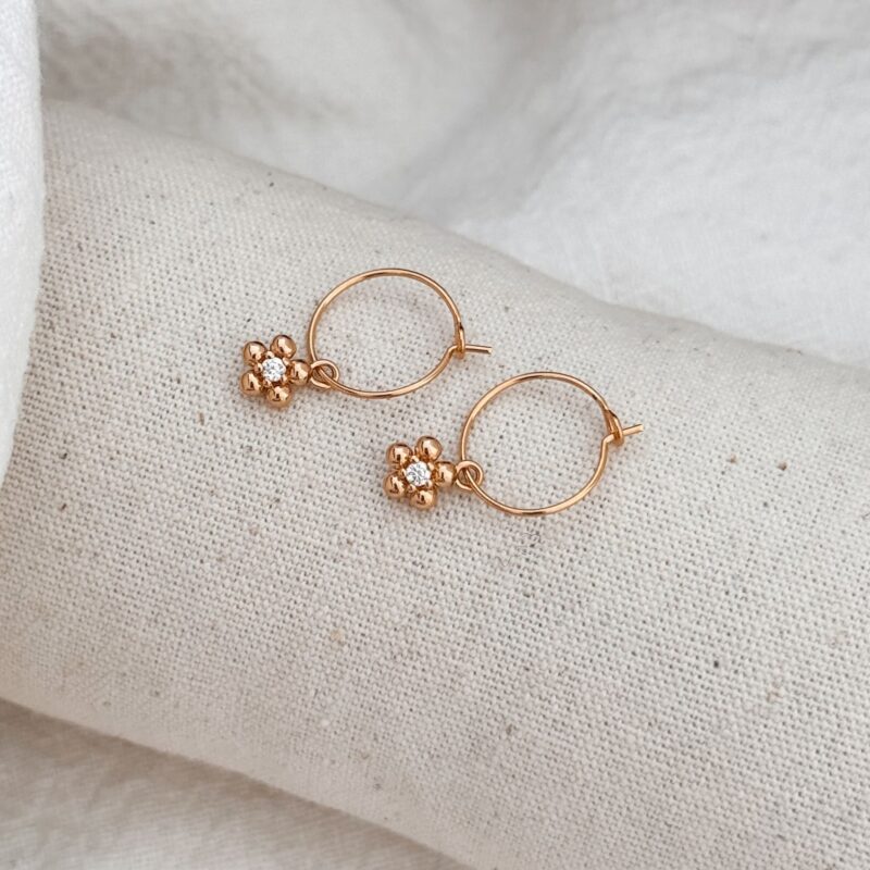 Boucles d'oreilles type créoles en plaqué or 3 microns 18 carats qui se composent d'un pendentif en forme de fleur, sertie au centre d'un oxyde de zirconium.