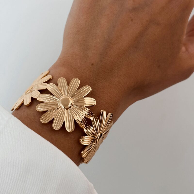 Craquez pour ce bracelet jonc pour femme en acier inoxydable doré, à la taille XXL, décoré sur tout le pourtour de fleurs, appelées marguerite. Le bracelet est ajustable et convient à tout type de poignet.