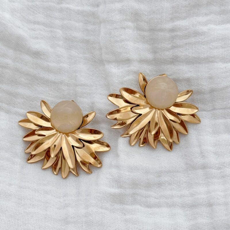 Boucles d'oreilles motif feuillage doré décoré d'un pierre rose ronde en acétate. Bijou de haute fantaisie en acier inoxydable doré. Dimensions de la boucle : 4,1 x 3,5 centimètres. Fermoir papillon sécurisé.