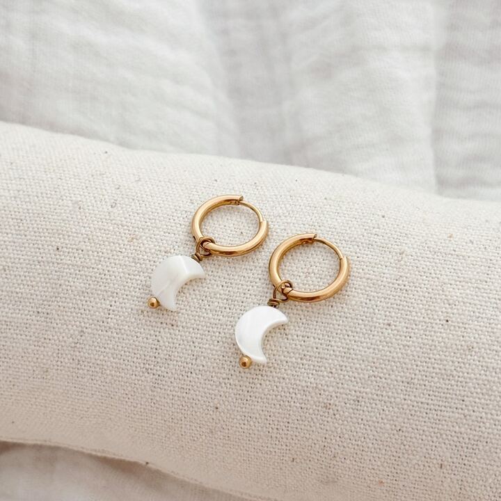 Paire de boucles d'oreilles pour femme en acier inoxydable doré qui se compose d'une mini créole sur laquelle est suspendue un petit croissant de lune en nacre.
