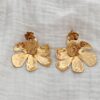 Boucles d'oreilles pour femme pendantes et imposantes en acier inoxydable doré. La paire se compose de deux empiècement en forme de fleur. La première 1,4 centimètres de diamètre et la seconde fleur mesure 4,5 centimètre de diamètre. La seconde pièce florale possède une pétale relevée en son centre. La paire de boucles d'oreilles est légère à porter malgré sa taille. Le bijou se ferme grâce un fermoir papillon sécurisé.