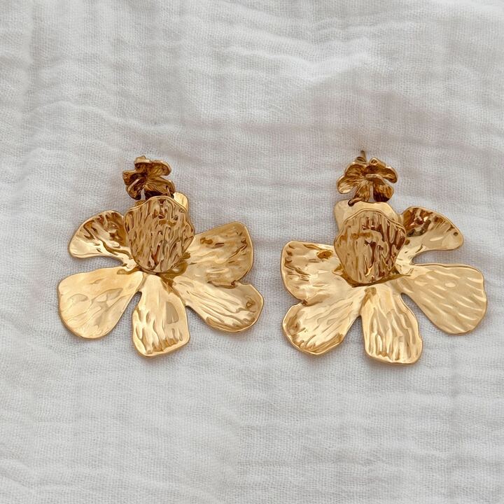 Boucles d'oreilles pour femme pendantes et imposantes en acier inoxydable doré. La paire se compose de deux empiècement en forme de fleur. La première 1,4 centimètres de diamètre et la seconde fleur mesure 4,5 centimètre de diamètre. La seconde pièce florale possède une pétale relevée en son centre. La paire de boucles d'oreilles est légère à porter malgré sa taille. Le bijou se ferme grâce un fermoir papillon sécurisé.