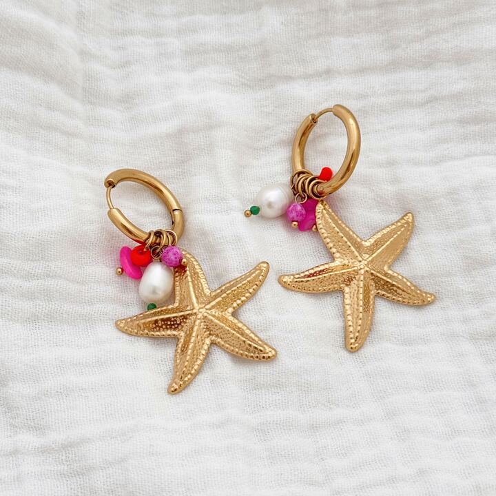 Boucles d'oreilles pendantes pour femme tendance été décorées de petites breloques colorées et d'une étoile de mer, tous suspendus à une petite créole. Le bijou est en acier inoxydable doré et est très léger à porter malgré sa taille imposante.