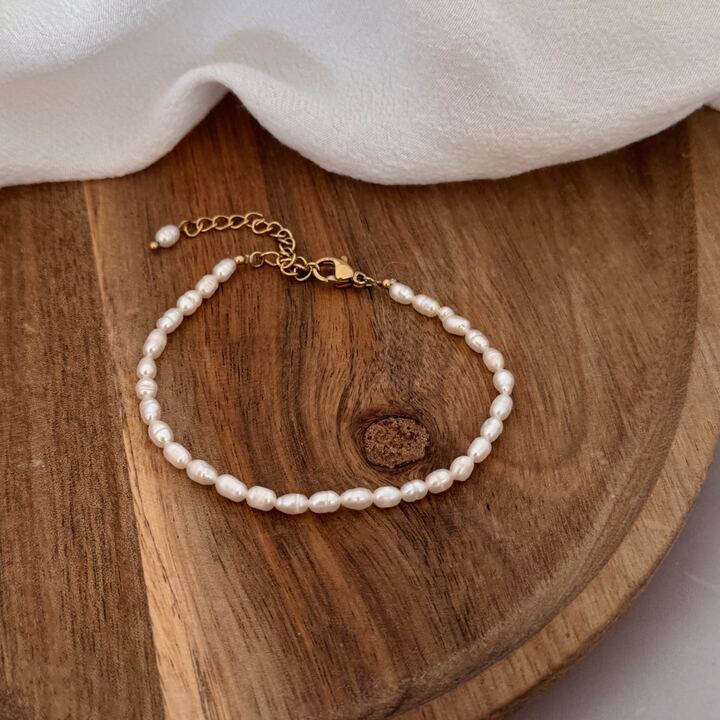 Bracelet élégant monté de perles naturelles appelées perles d'eau douce. Les perles sont de forme ovale. Le bracelet est réglable jusqu'à 21 centimètre et se ferme grâce à un fermoir mousqueton ovale.