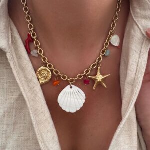 Collier pour femme en acier inoxydable doré qui résiste à l'eau. Le bijou est composé d'une chaîne à larges maillons sur laquelle sont disposés plusieurs charms : étoile de mer, coquillage en nacre, coeur en nacre, un corail rouge etc... Tour de cou ajustable.