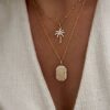 Association de colliers en plaqué or pour femme. Le premier collier est décoré d'un pendentif en forme de palmier. Le second se compose d'un pendentif personnalisable avec une gravure, de forme rectangulaire.