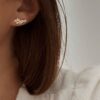 Boucles d'oreilles grimpantes sur le lobe pour femme en plaqué or 3 microns 18 carats. Le bijou se compose d'un design en forme de grappe de petites fleurs. Chaque fleur est sertie d'un petit oxyde de zirconium en son centre.