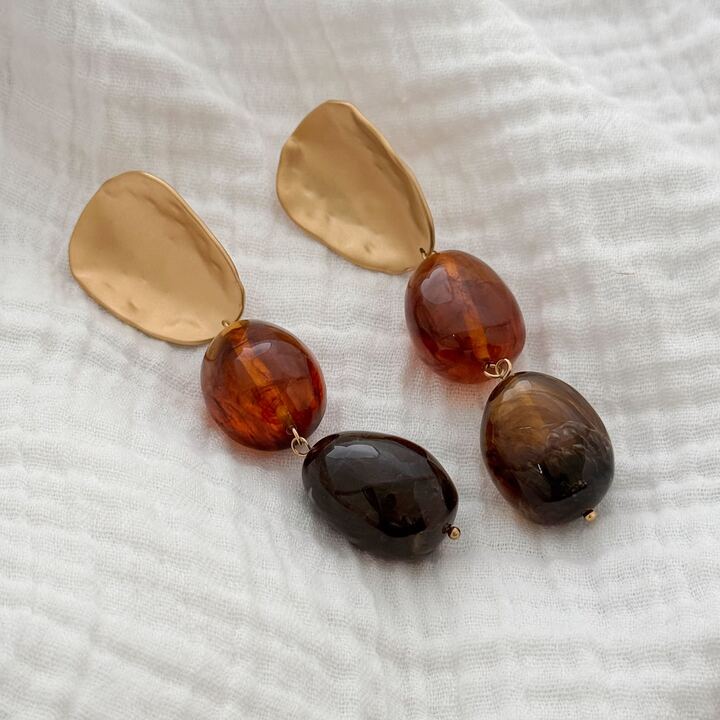 Boucles d'oreilles pendantes en acier inoxydable doré décorée de deux grosses perles marrons et d'un empiècement doré, recourbé.