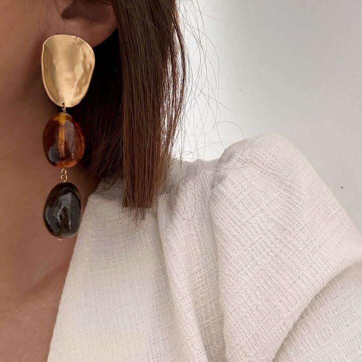 Boucles d'oreilles pendantes pour femme très légères à porter. Elles sont composées d'une pièce dorée recourbée sur laquelle sont suspendues deux grosses perles marrons. Les boucles d'oreilles sont imposantes, elles mesurent 8,5 centimètres de longueur.