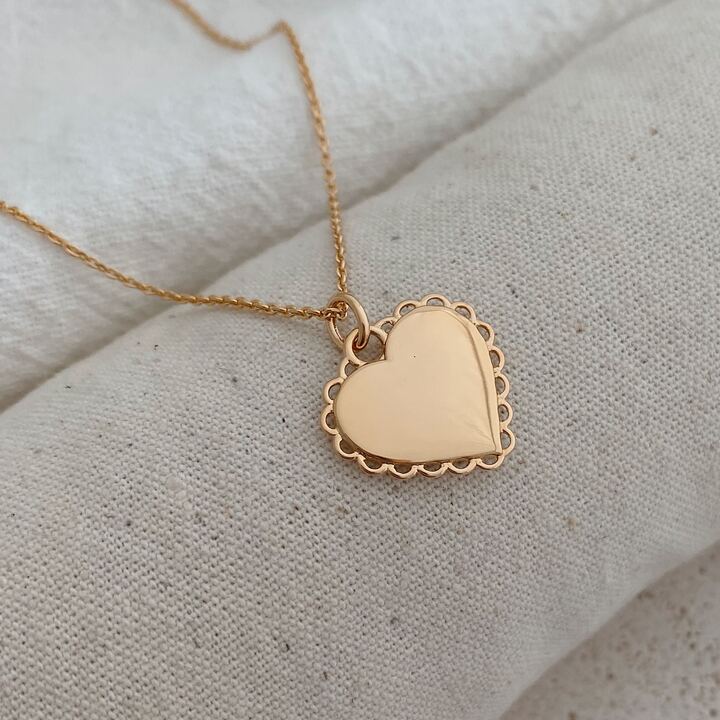 Collier pour femme en plaqué or 3 microns 18 carats qui se compose d'une chaîne classique et d'un pendentif en forme de coeur décoré d'un pourtour effet dentelle. Le pendentif coeur peut resté vierge et lisse ou bien être personnalisée avec une jolie gravure sur le recto et/ou le verso. Le médaillon mesure 1,9 centimètres de longueur et 1,8 centimètres de largeur. La chaîne est disponible avec plusieurs longueurs de tour de cou : 40, 45, 50, 60 70 et 80 cm Vous pouvez donc le porter en ras-de-cou comme en sautoir.