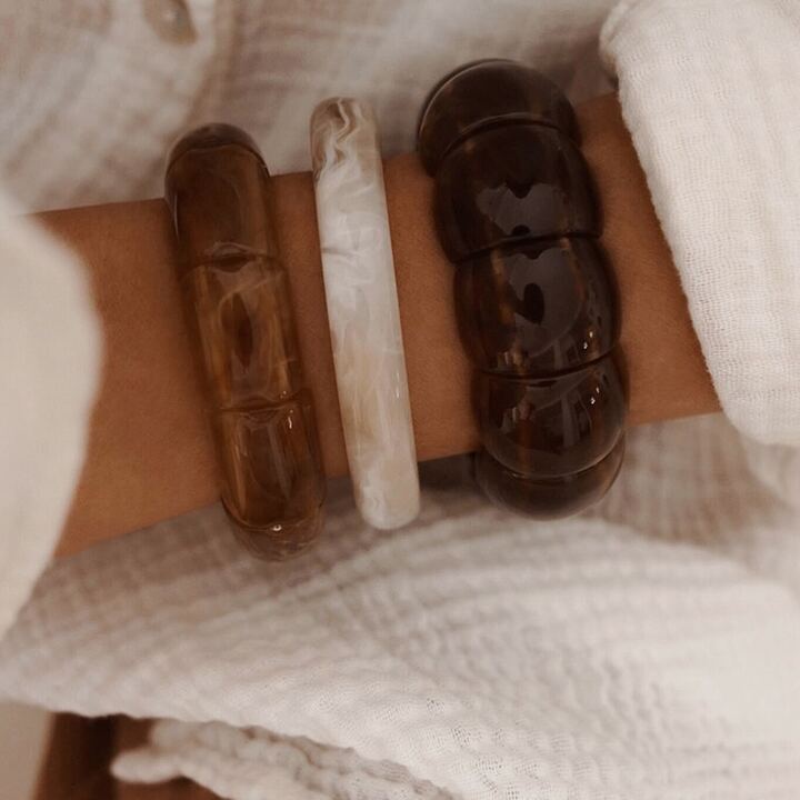 Association de bracelets élastiques composés de grosses perles marrons et beiges.