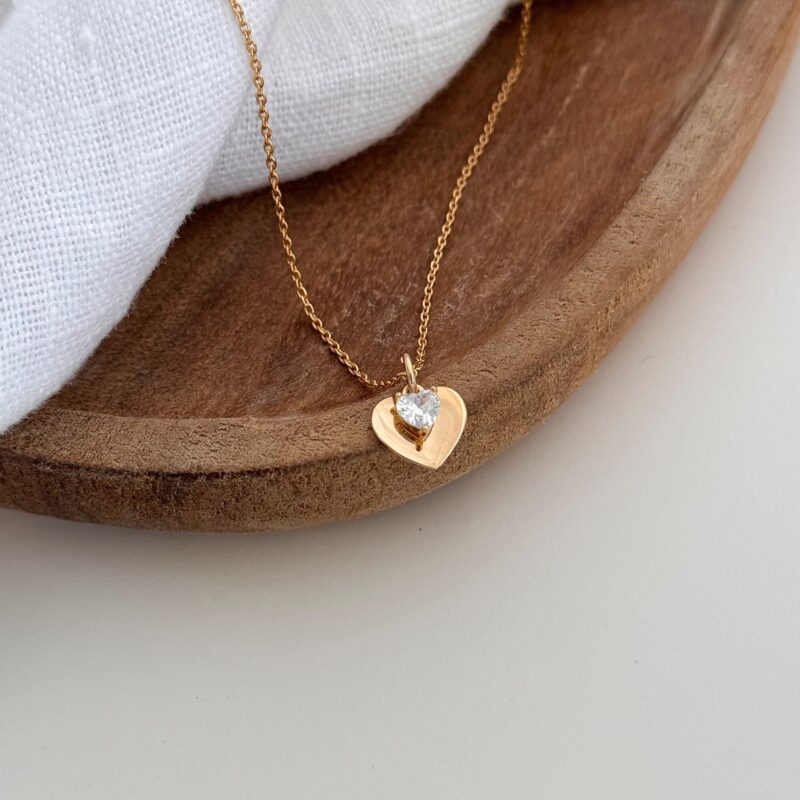 Collier pour femme en plaqué or 3 microns 18 carats, raffiné et élégant. Le bijou se compose d'une simple chaîne sur laquelle est glissé un pendentif type médaille en forme de coeur. Le pendentif est monté d'un petit coeur en oxyde de zirconium. Plusieurs tailles de tour de cou sont disponibles. Fermoir sécurisé type mousqueton rond.