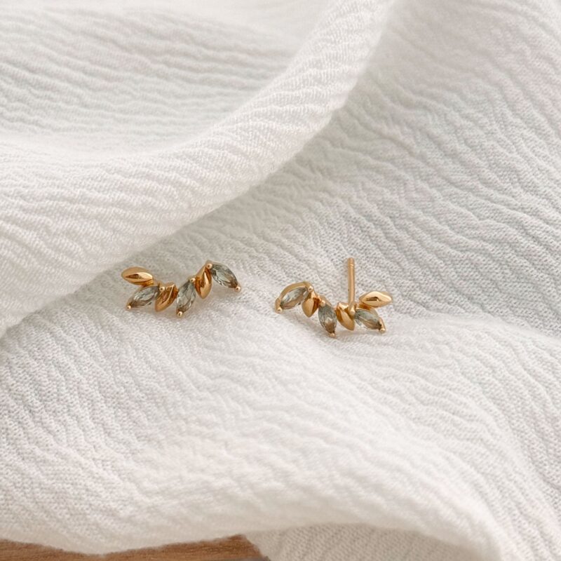 Boucles d'oreilles montantes en plaqué or 3 microns 18 carats. Ce bijou grimpant, viendra épouser la forme de votre lobe avec raffinement. La paire se compose de petite pétales de fleur ovale dorée ou bien serties d'oxydes de zirconium vert. Les boucles d'oreilles se ferment grâce à un fermoir papillon.
