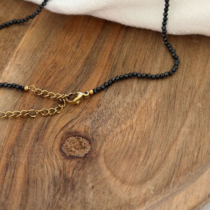 Collier fin pour femme en acier inoxydable doré décoré de petites perles noires enfilées à la main.