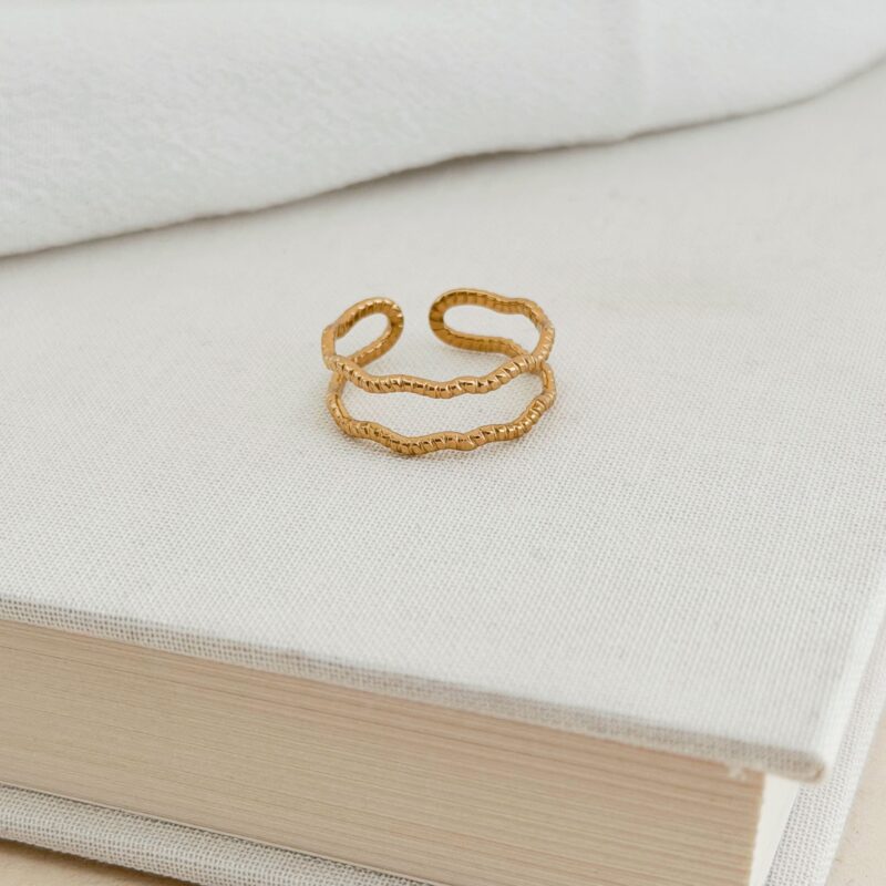 Bague en acier inoxydable doré Bijou double rangs au fini irrégulier motif vague Largeur : 0.7 cm Taille ajustable de 52 à 56 Cette bague est garantie sans nickel, sans cadmium, sans sel de plomb Elle résiste à l’eau et ne noircit pas