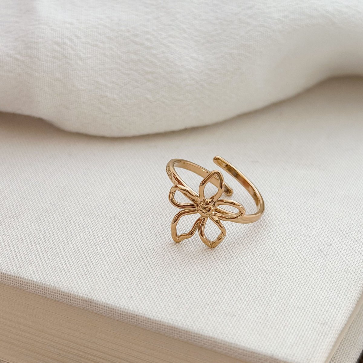 Bague en acier inoxydable doré Design : Bijou décoré d'une fleur ajourée à la forme irrégulière au fini martelé Taille ajustable de 54 à 58 Diamètre de la fleur : 1.1 x 0.9 cm