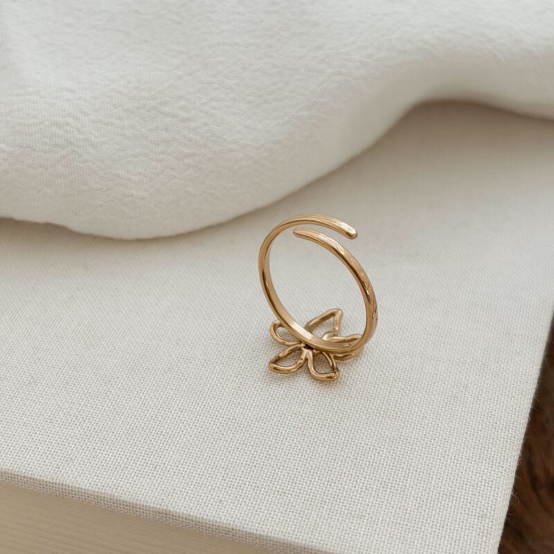 Bague en acier inoxydable doré Design : Bijou décoré d'une fleur ajourée à la forme irrégulière au fini martelé Taille ajustable de 54 à 58 Diamètre de la fleur : 1.1 x 0.9 cm