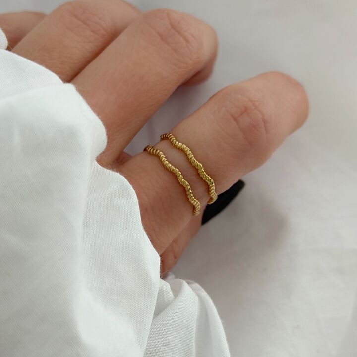 Bague ajustable pour femme à petit prix acier inoxydable doré. Le bijou se compose de deux anneaux motif vague.