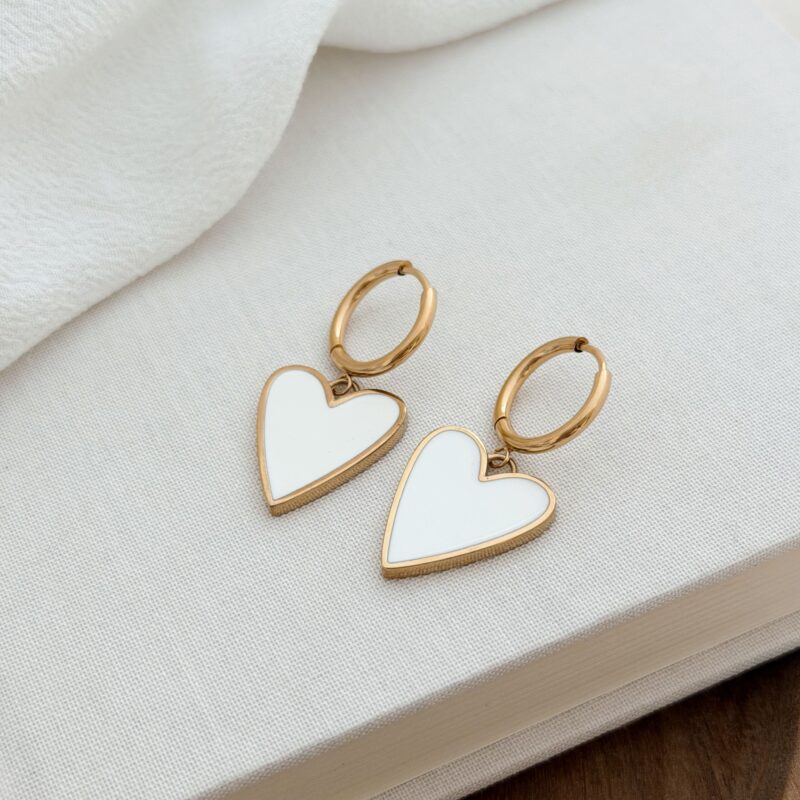 Collection Amour Boucles d'oreilles type créoles pendantes en acier inoxydable doré Le bijou se compose d'une fine créole et d'une pendentif en forme de cœur, émaillé en blanc Diamètre créole : 1,5 cm Dimensions cœur : 1,7 x 2 cm Longueur boucle d'oreille : 3,6 cm Fermoir charnière Cette paire de boucles d'oreilles est garantie sans nickel, sans cadmium, sans sel de plomb. Elle résiste à l’eau et ne noircit pas