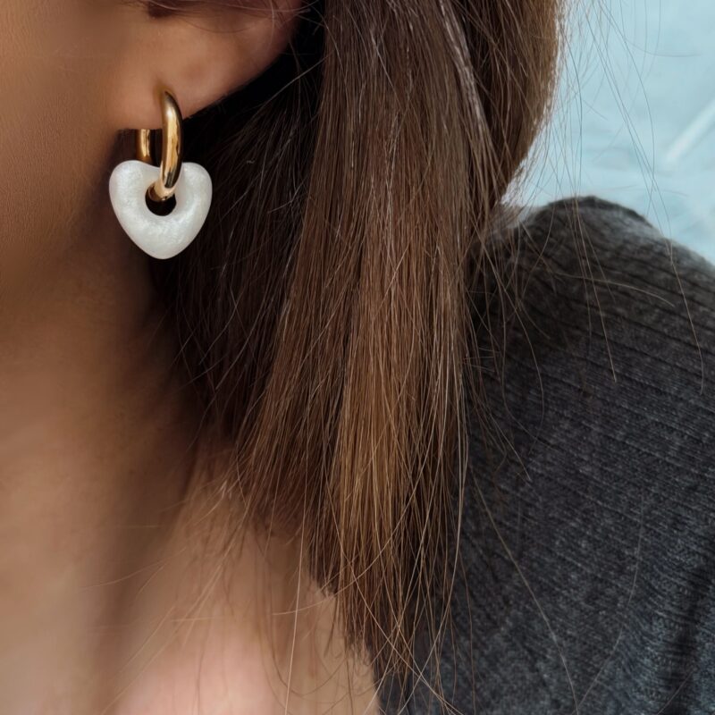 Boucles d'oreilles pour femme en acier inoxydable qui se compose d'une créole et d'un petit coeur blanc.