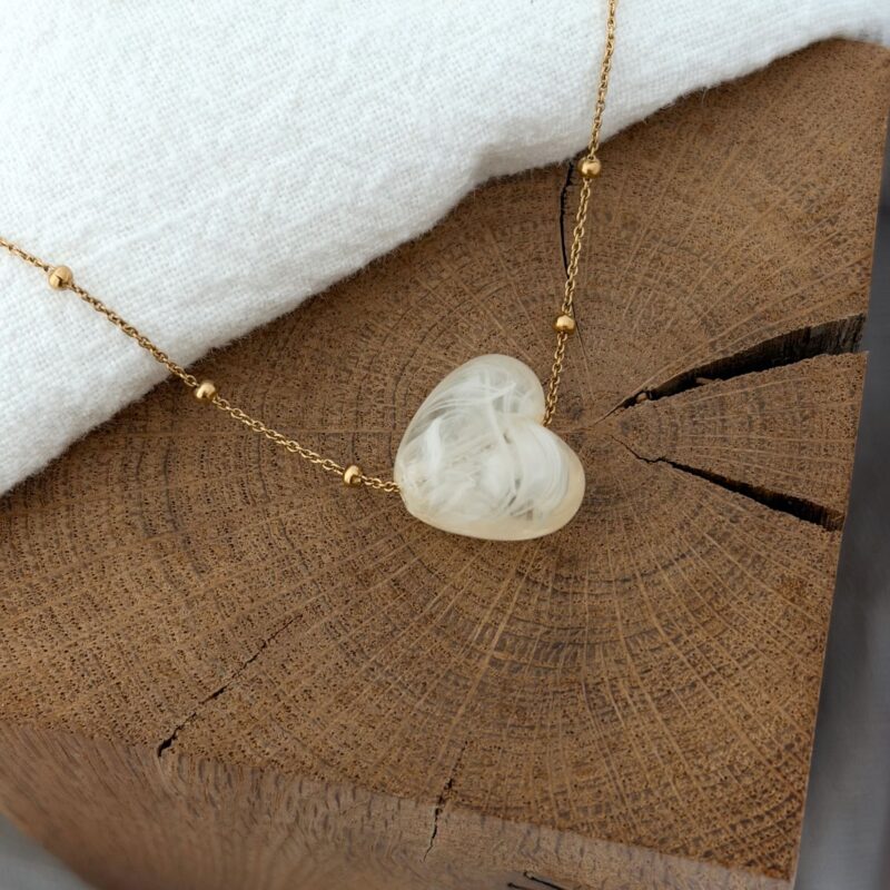 ll Création Jolie Demoiselle ll Collier en acier inoxydable doré  Design : Bijou décoré d'une fine chaîne boules sur laquelle est glissé un cœur légèrement bombé acrylique disponible en plusieurs coloris : Beige, marron et rose tous nuancés Dimension du cœur : 1.7 cm x 1.9 cm  Tour de cou ajustable de : 50 cm à 55 cm Fermoir mousqueton Ce bijou est garanti sans nickel, sans cadmium, sans sel de plomb Il résiste à l’eau et ne noircit pas