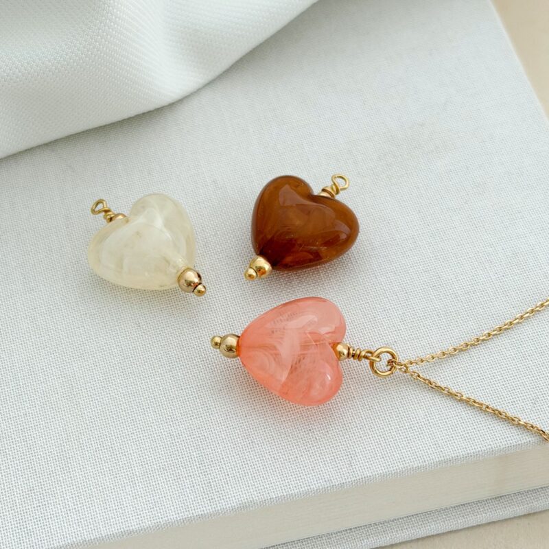 Collier femme en plaqué or qui se compose d'une fine chaîne et de pendentifs en forme de coeur bombé coloré.