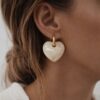 Boucles d'oreilles pendantes pour femme en acier inoxydable doré décoré d'un gros coeur coloris beige.