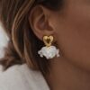 Boucles d'oreilles pour femme légères et tendance. La boucle se compose d'un coeur bombé lisse de couleur doré sur lequel sont suspendus plusieurs pétales blancs.