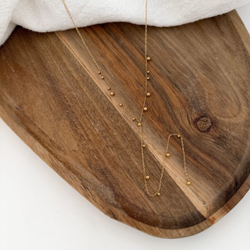 Collier pour femme très tendance en acier inoxydable doré. Le collier est décoré de petites billes.