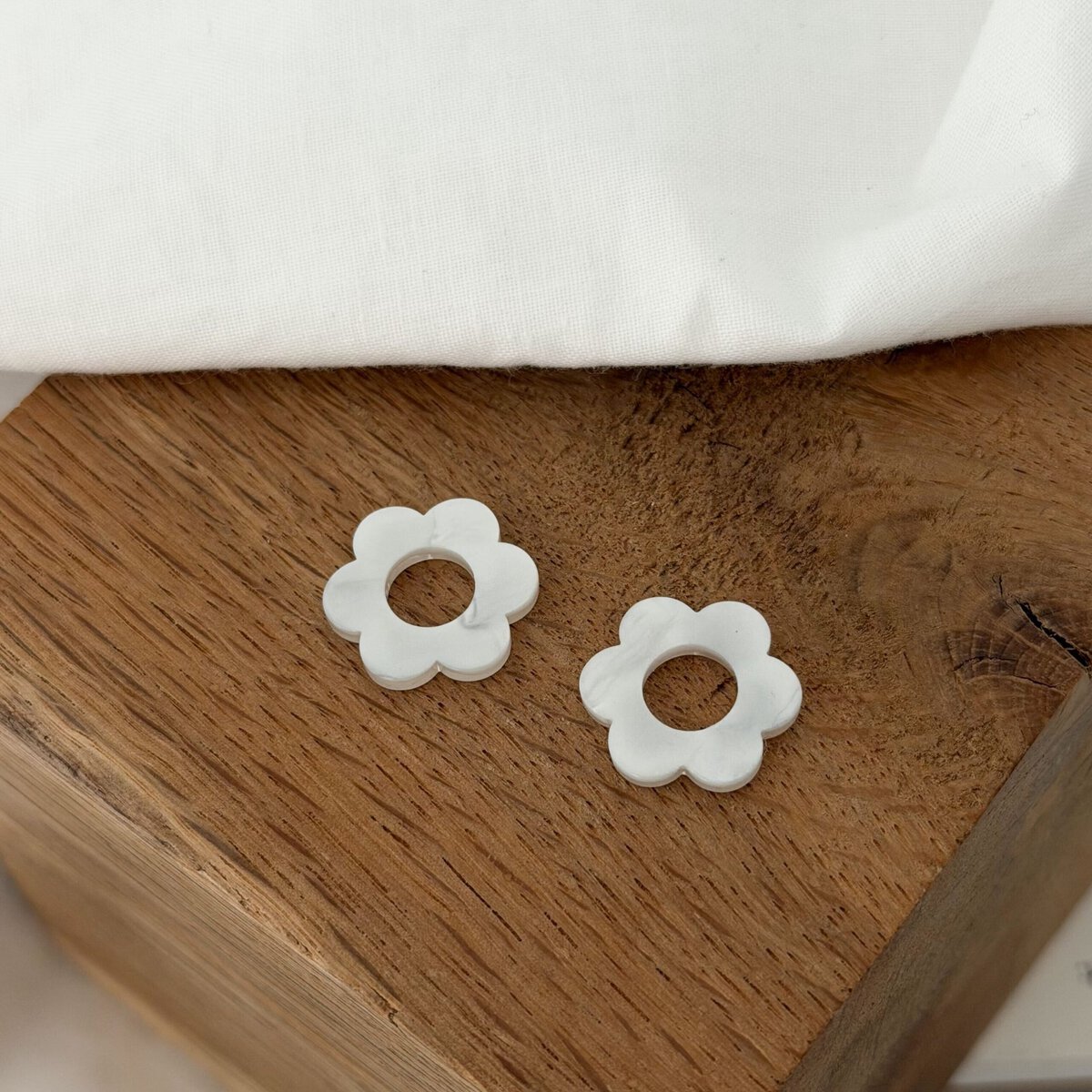 Boucles d'oreilles interchangeables pour femme. Découvrez notre paire de fleurs en acétate, coloris blanc nacré. Ce bijou sera à glisser sur votre paire de boucles d'oreilles type créoles favorite ! Diamètre de la fleur : 0,8 centimètres.