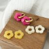 Coffret boucles d'oreilles interchangeables avec fleurs en acétate, couleurs rose, jaune et beige.