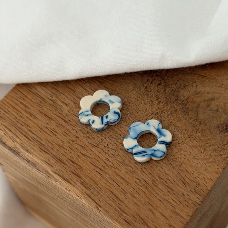 Boucles d'oreilles interchangeables pour femme. Découvrez notre paire de fleurs en acétate, coloris bleu et blanc. Ce bijou sera à glisser sur votre paire de boucles d'oreilles type créoles favorite ! Diamètre de la fleur : 0,8 centimètres.